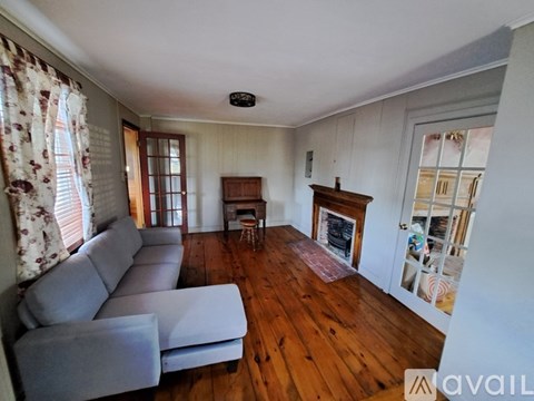 A living room with a grey couch and wooden floors.