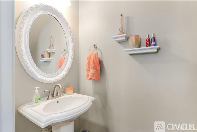 A bathroom with a white sink and a round mirror.