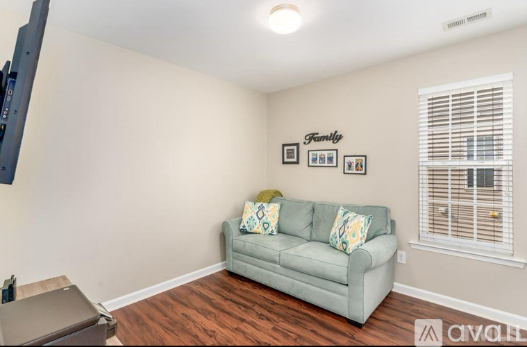 A living room with a grey couch and a flat screen TV mounted on the wall.