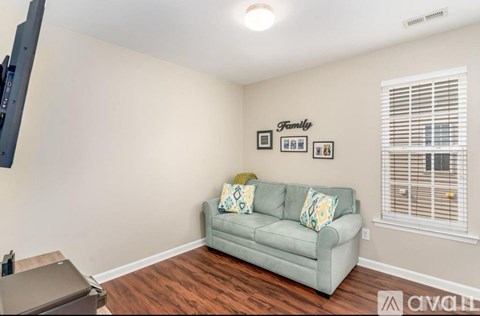 A living room with a grey couch and a flat screen TV mounted on the wall.