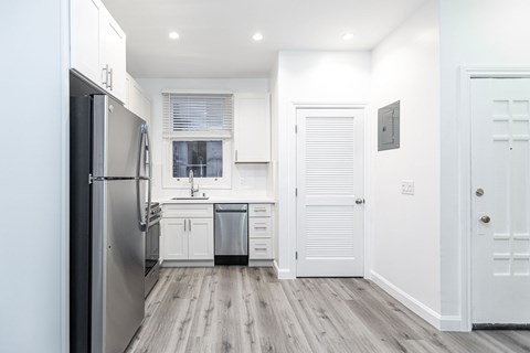 A kitchen with white cabinets and a stainless steel refrigerator.