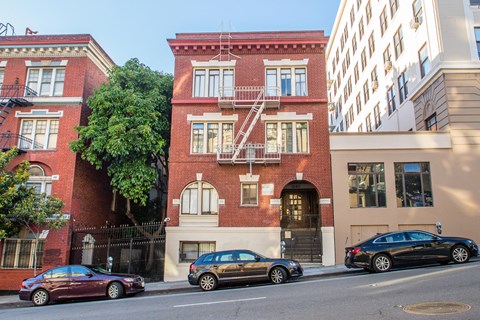 A red brick building with a black car parked in front.