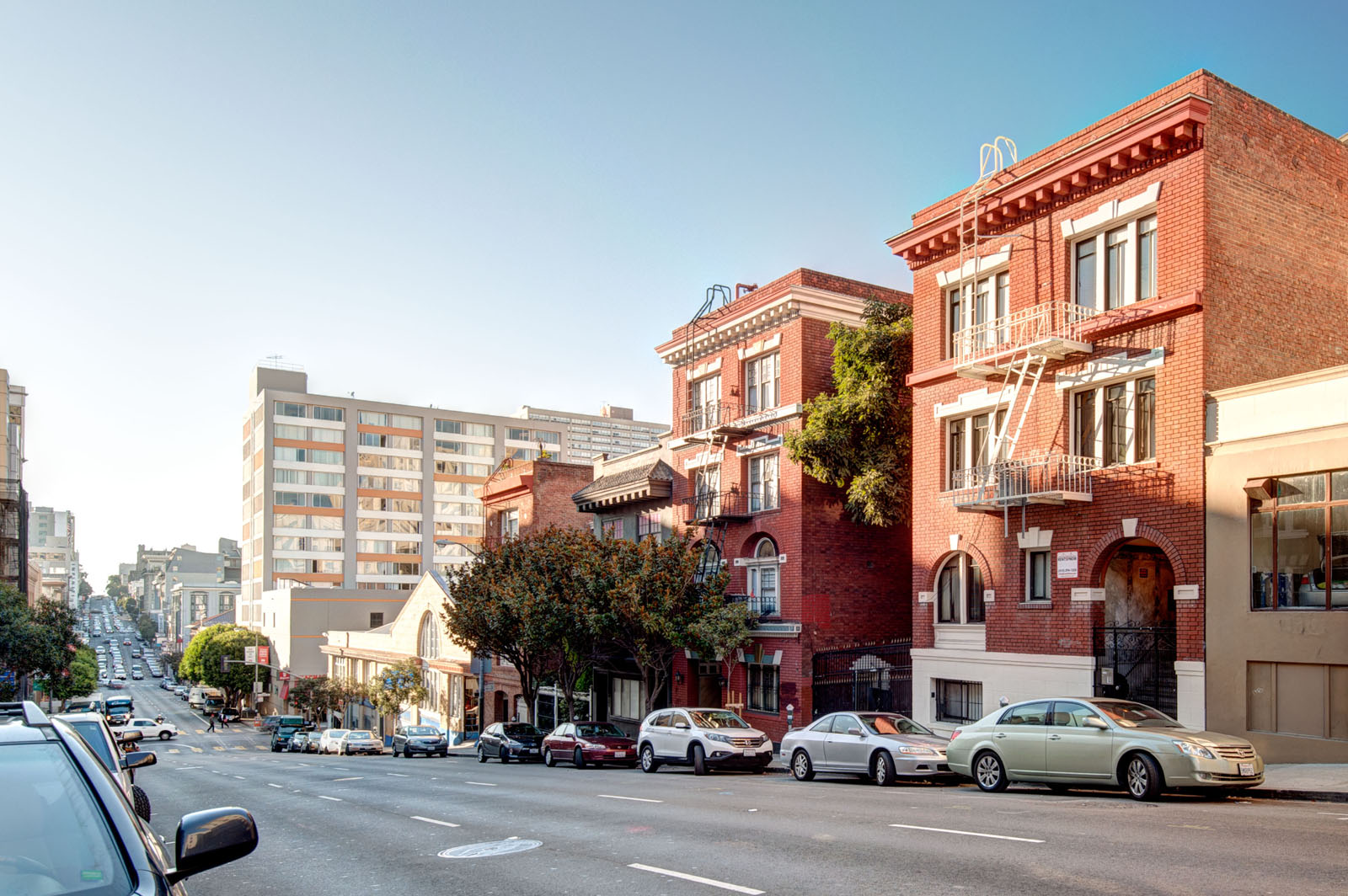 Cars are driving on a street with buildings on both sides.