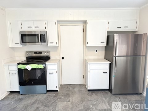 A kitchen with white cabinets and a stainless steel refrigerator.