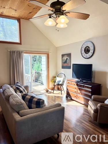 A living room with a grey couch and a wooden ceiling fan.