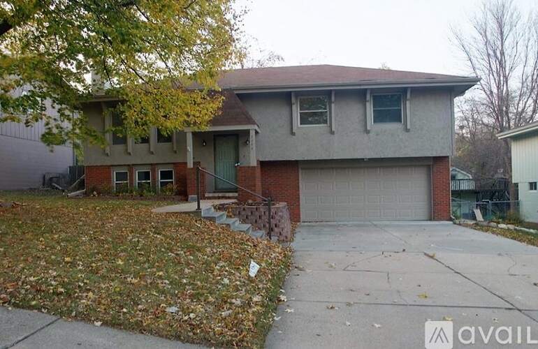 A house with a garage and a driveway covered in fallen leaves.