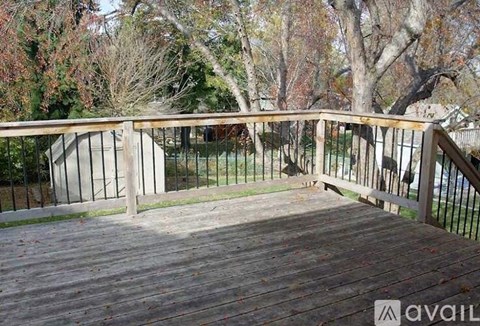A wooden deck with a metal railing and trees in the background.
