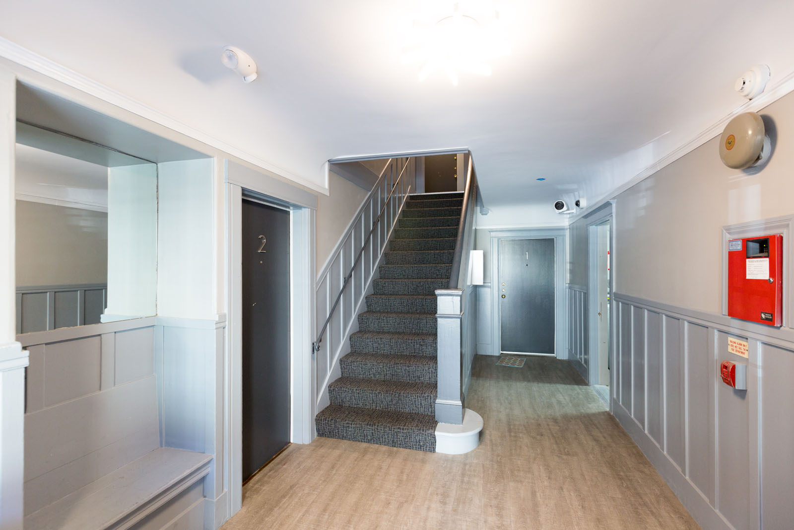 A staircase with a grey carpeted runner and a wooden handrail.