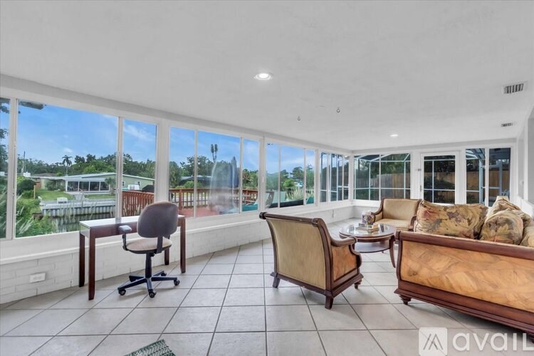 A living room with a couch, chair, and desk with a view of the outdoors.