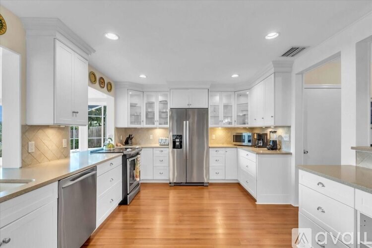 A modern kitchen with white cabinets and a wooden floor.
