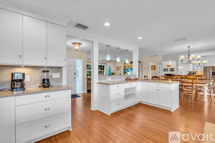 A spacious kitchen with white cabinets and a wooden floor.