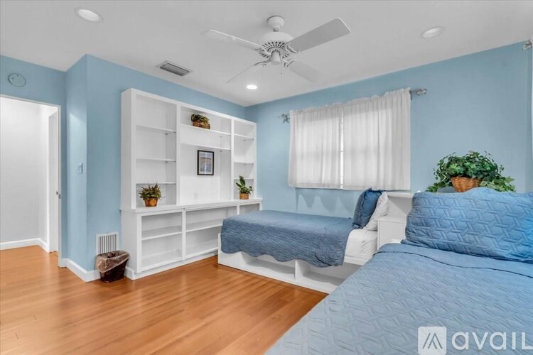 A bedroom with a bed, a ceiling fan, and a window with curtains.