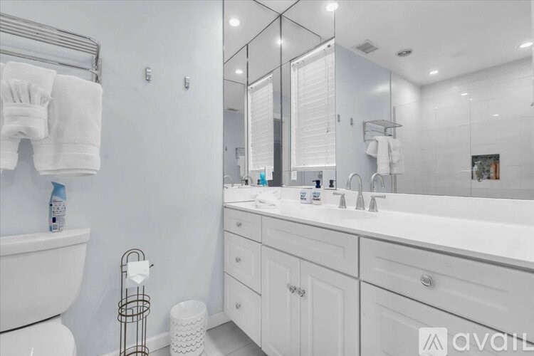 A white bathroom with a large mirror and a white sink.