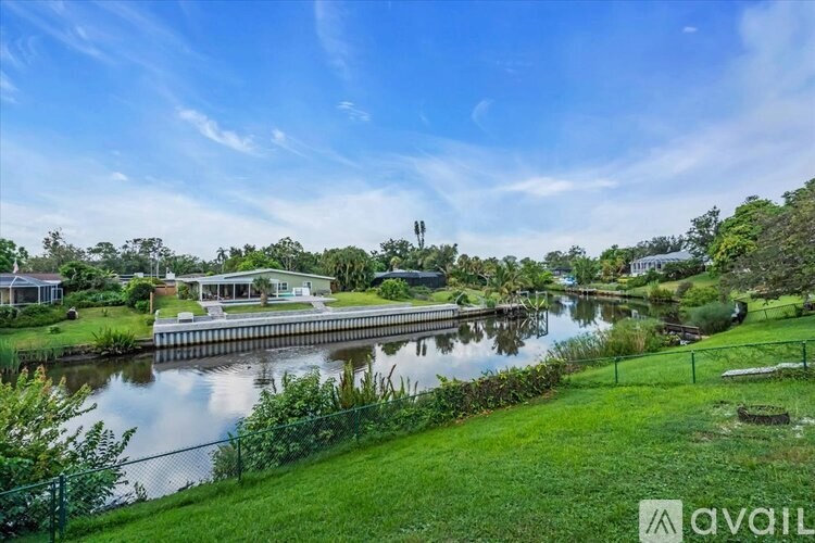 A living room with a grey couch, a grey ottoman, a television, and a ceiling fan.