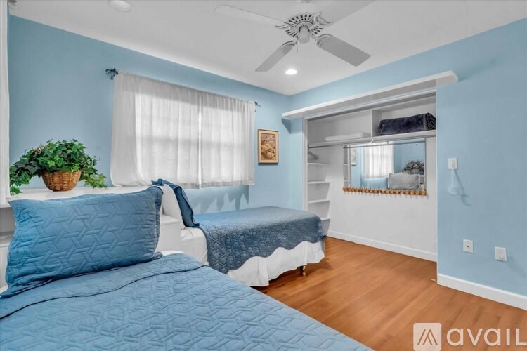 A bedroom with a blue bedspread and a ceiling fan.
