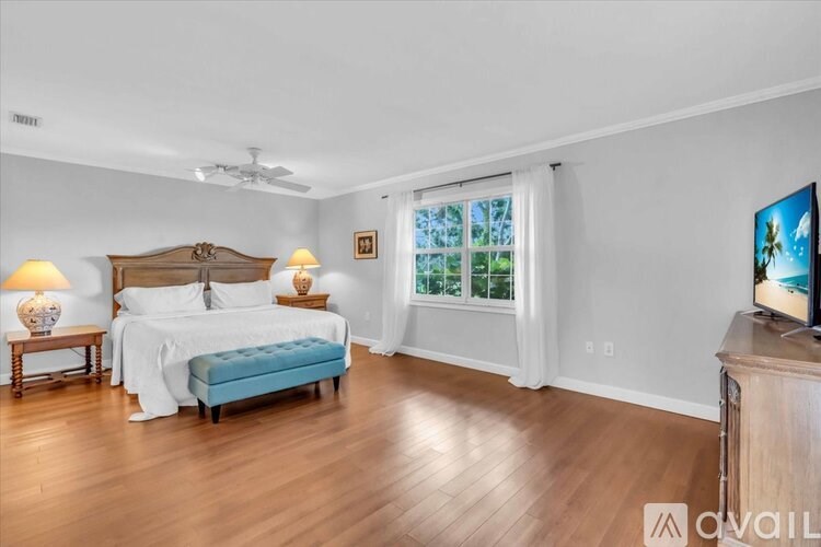 A bedroom with a large bed, a bench, and a television.