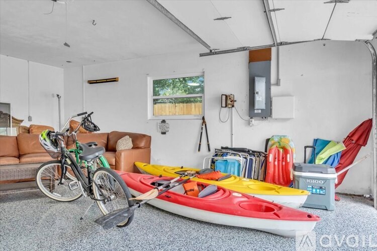 A room with a bicycle, a kayak, and a red chair.
