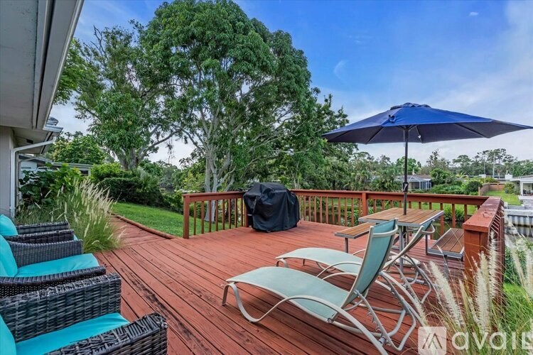 A deck with a blue umbrella and chairs.