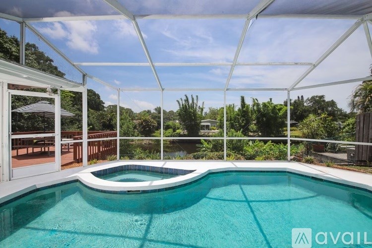 A pool enclosed by a white frame with trees in the background.