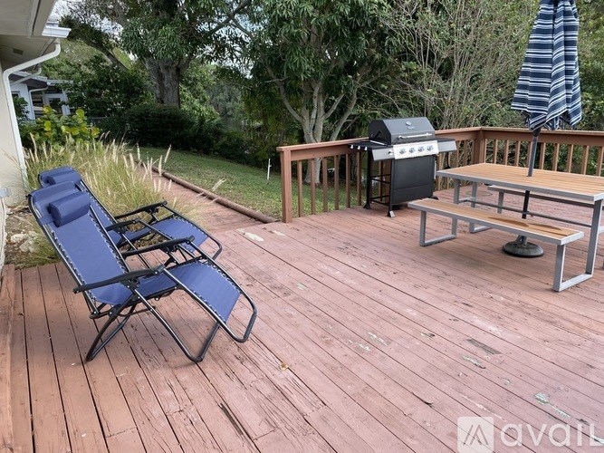 A wooden deck with a grill and two chairs.