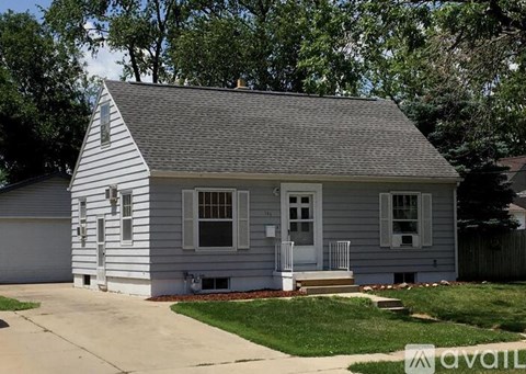A small house with a grey roof and white siding is for sale.
