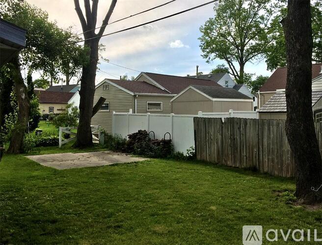A backyard with a white fence and a tree.