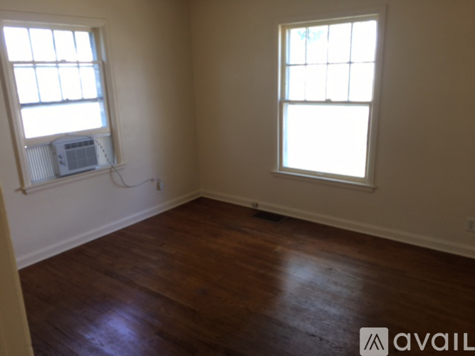 A room with wooden floors and two windows.