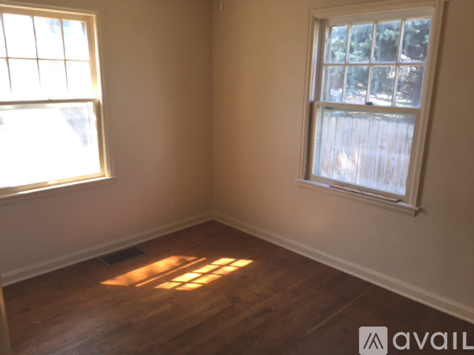 A room with wooden floors and two windows.