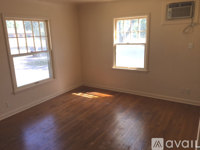 A room with wooden floors and two windows.