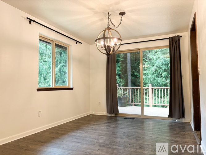 A room with a chandelier, sliding glass doors, and a wooden floor.