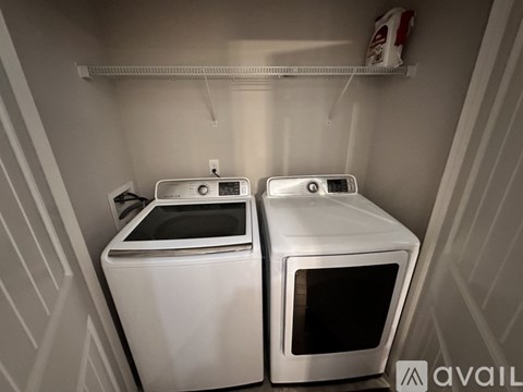 Two white microwaves are sitting on a shelf in a kitchen.
