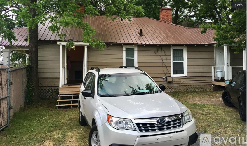 A silver Subaru car is parked in front of a house.