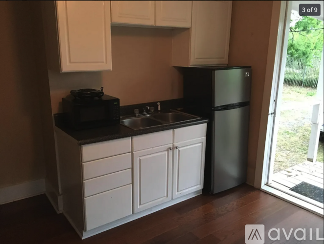 A kitchen with white cabinets and a black fridge.