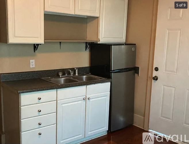 A kitchen with white cabinets and a black refrigerator.