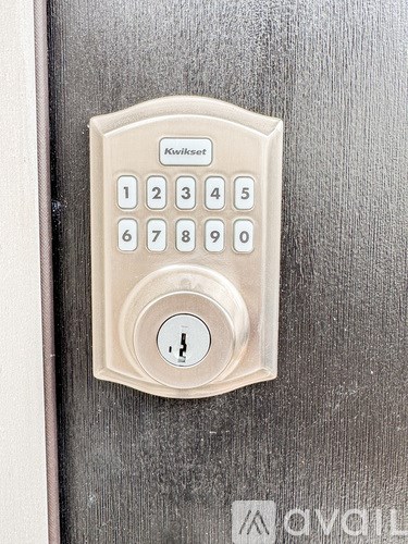 A Kwikset keypad is mounted on a wooden door.