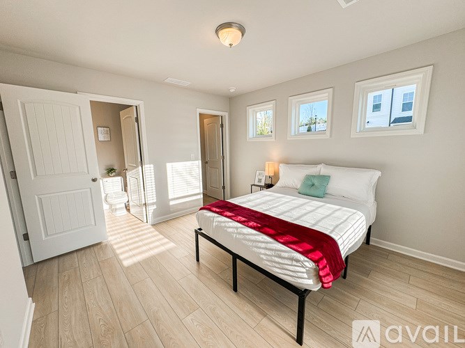 A bedroom with a bed, a window, and a door.