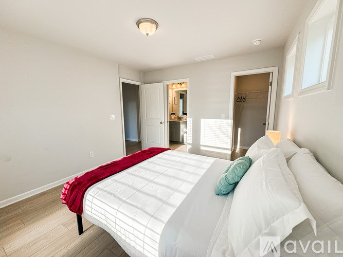 A bedroom with a bed, a window, and a door.