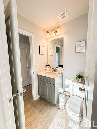 A bathroom with a sink, toilet, and mirror.