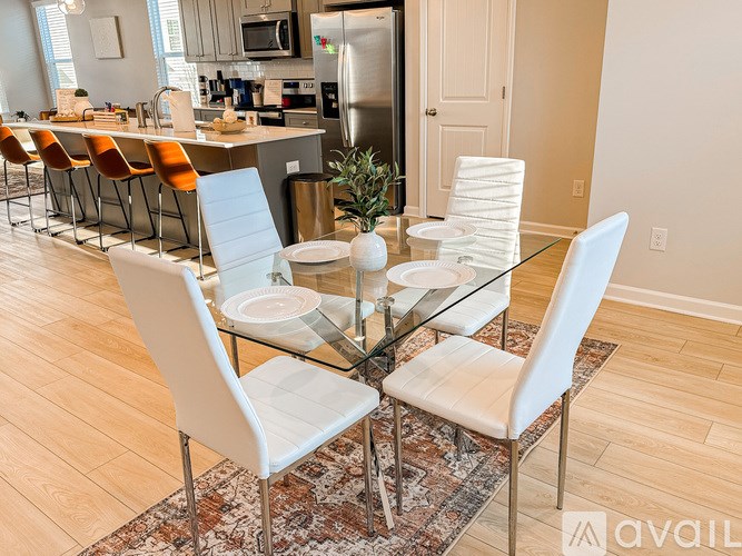 A glass dining table with white chairs in a modern kitchen.