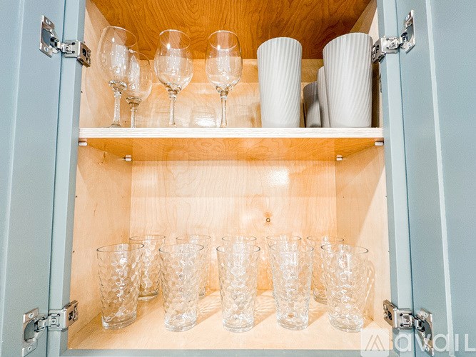 A cabinet with glasses and cups on the shelf.