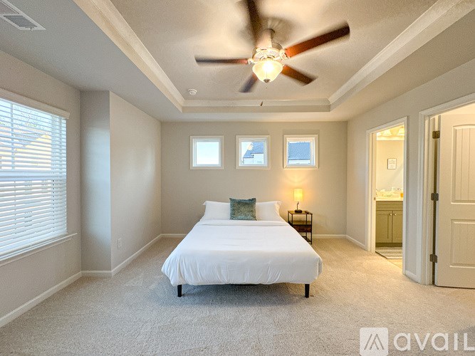 A bedroom with a bed, a ceiling fan, and a window with blinds.