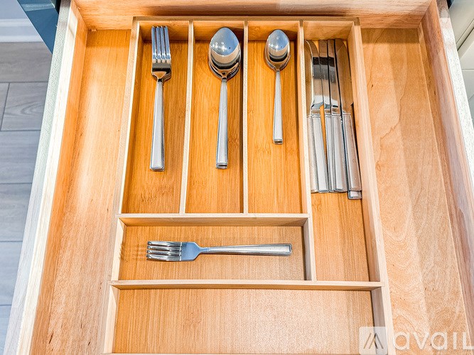 A drawer with utensils and a fork in the bottom left.