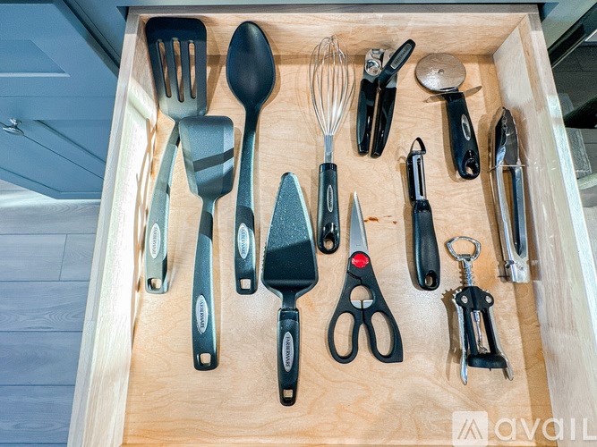 A drawer full of kitchen utensils including scissors, spatula, and whisk.