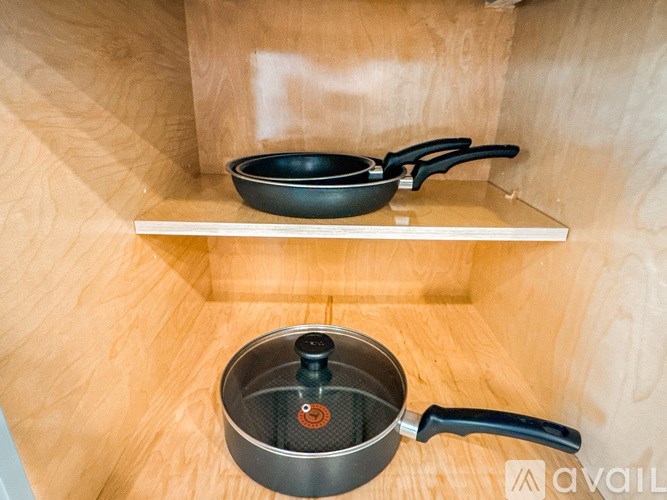 A pan with a lid sits on a shelf in a kitchen.