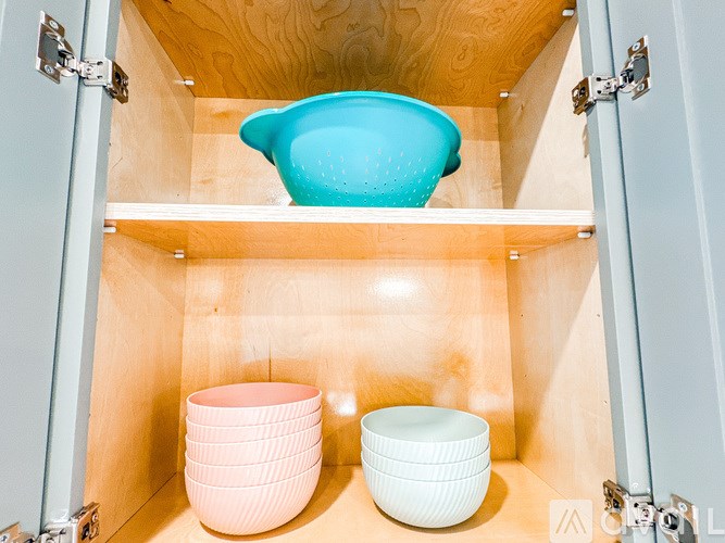 A blue bowl is on top of a shelf in a cabinet.