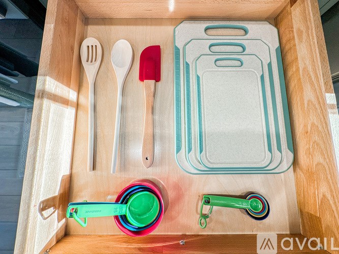A wooden box contains a set of utensils and a spatula.