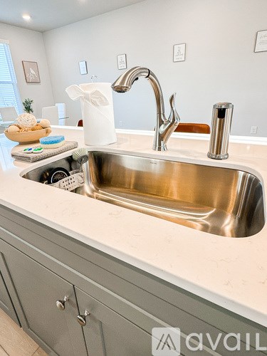 A modern kitchen with a stainless steel sink and grey cabinets.