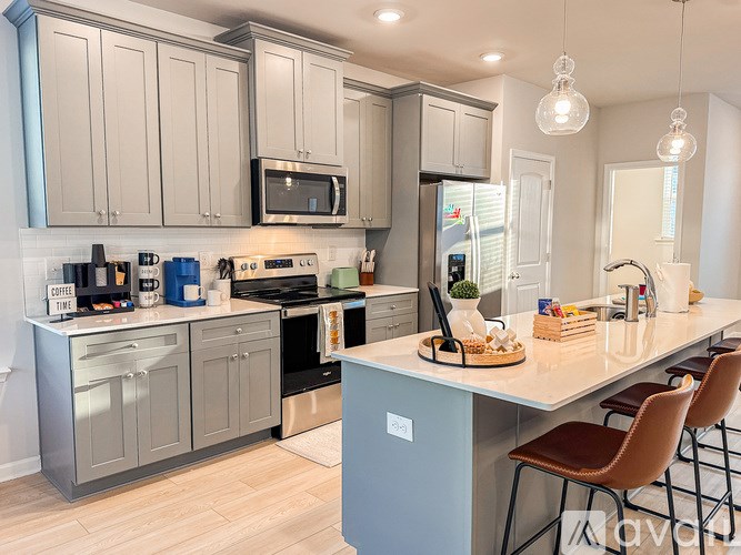 A kitchen with a white counter top and grey cabinets.