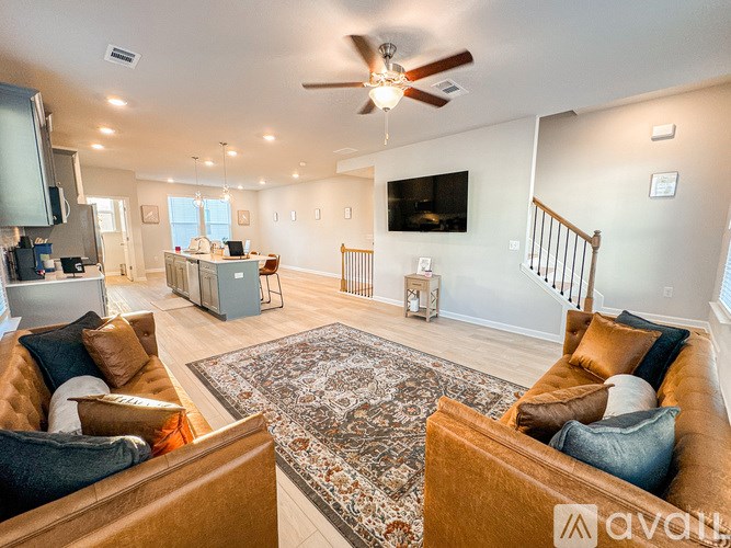 A living room with a brown couch and a rug in the center.