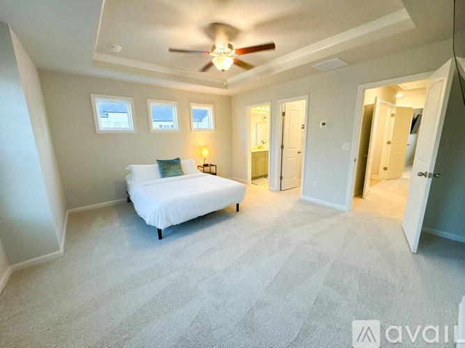 A bedroom with a bed, a ceiling fan, and a window.